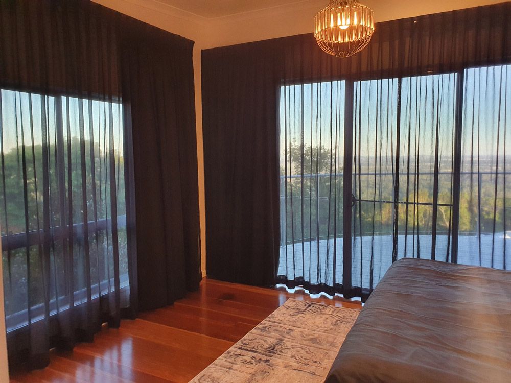 A Bedroom With Sliding Glass Doors and Black Curtains — Artizen Curtains in Mooloolaba, QLD