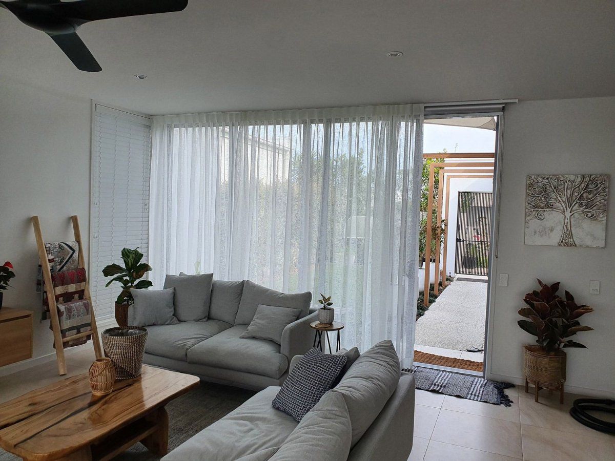 A Living Room With a Couch, Table, and Ceiling Fan — Artizen Curtains in Mooloolaba, QLD