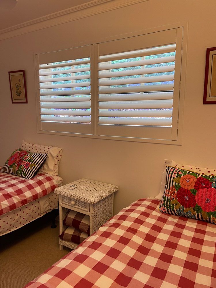 A Bedroom with Two Beds, a Nightstand , and A Window with Shutters — Artizen Curtains in Mooloolaba, QLD