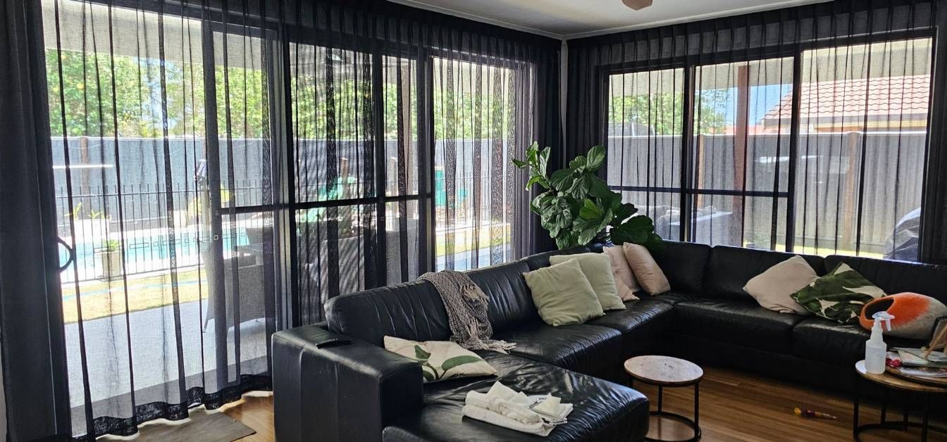 A Living Room With a Black Couch and Black Curtains — Artizen Curtains in Mooloolaba, QLD