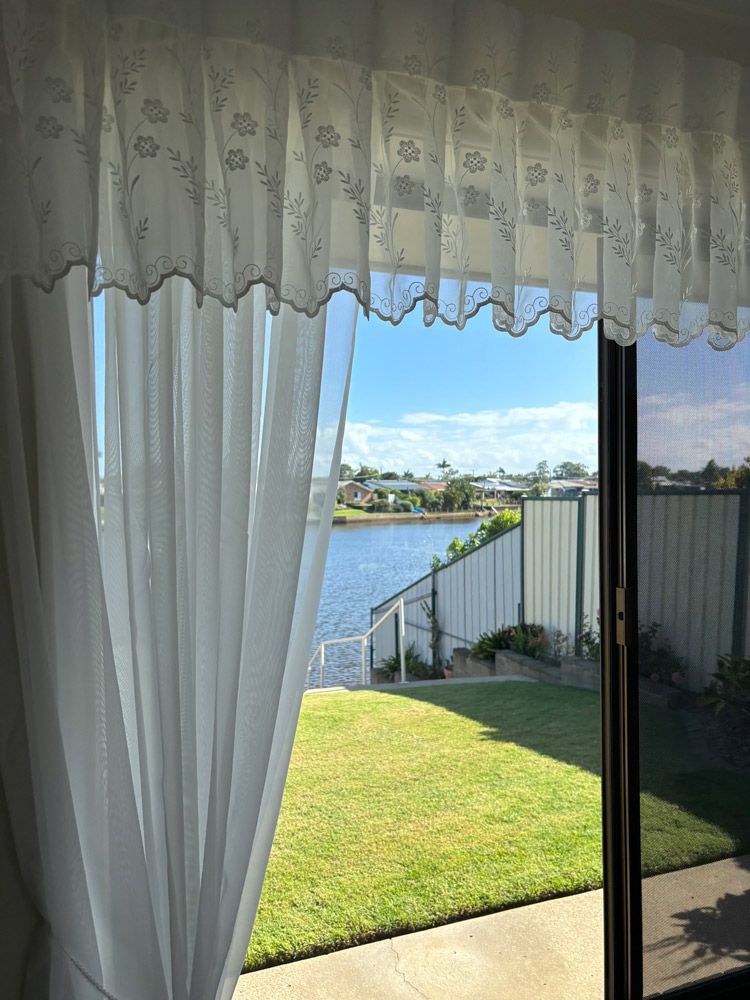 A View of A Lake Through a Window with White Curtains — Artizen Curtains in Mooloolaba, QLD