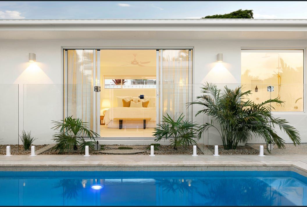 A White House With a Swimming Pool in Front of It — Artizen Curtains in Mooloolaba, QLD