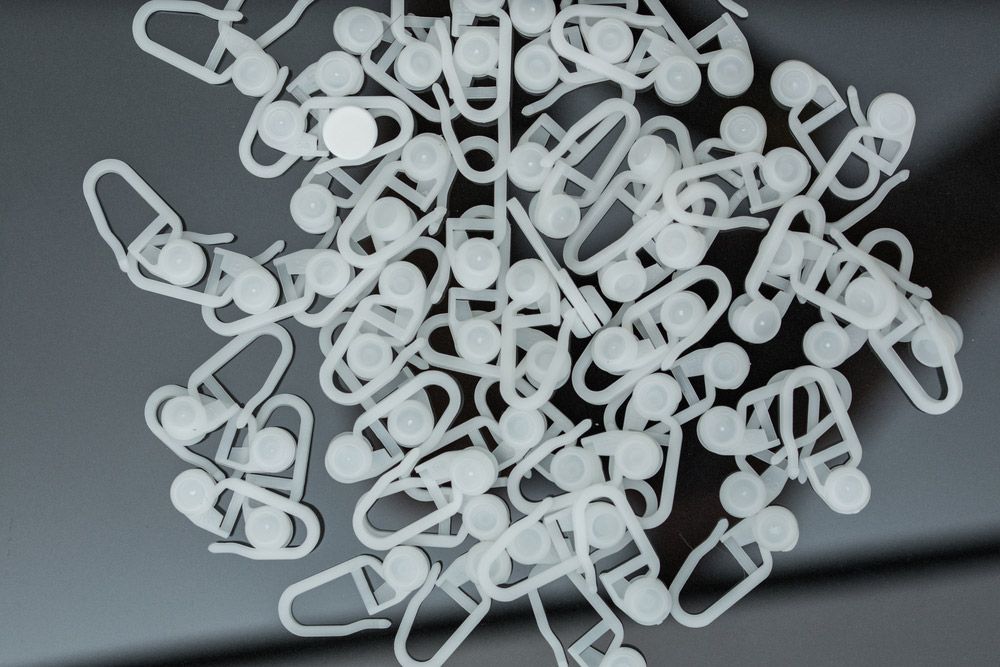 A Pile of White Curtain Hooks on a Black Surface — Artizen Curtains in Mooloolaba, QLD