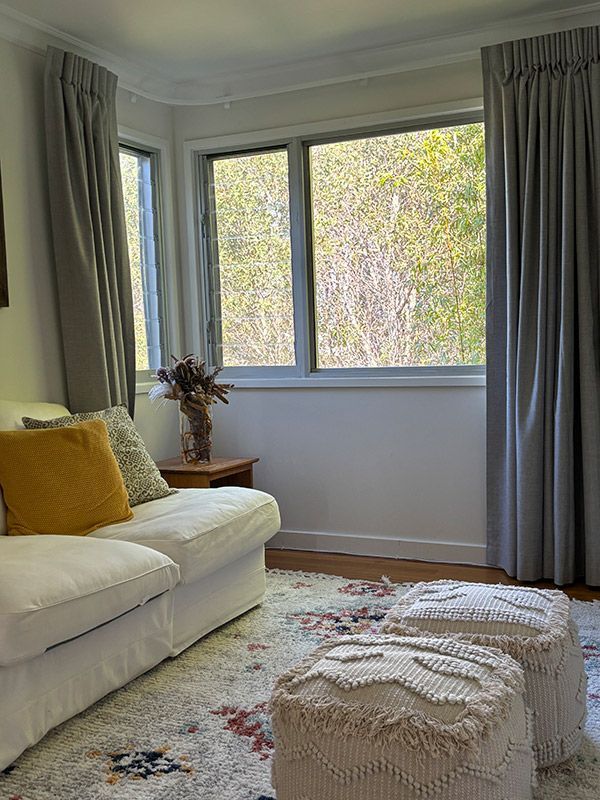 A Living Room With a White Couch, Two Ottomans and a Window