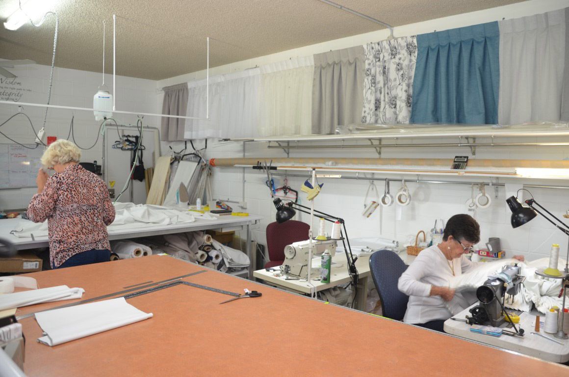 A Woman Is Sitting at A Table in A Sewing Room — Artizen Curtains in Mooloolaba, QLD