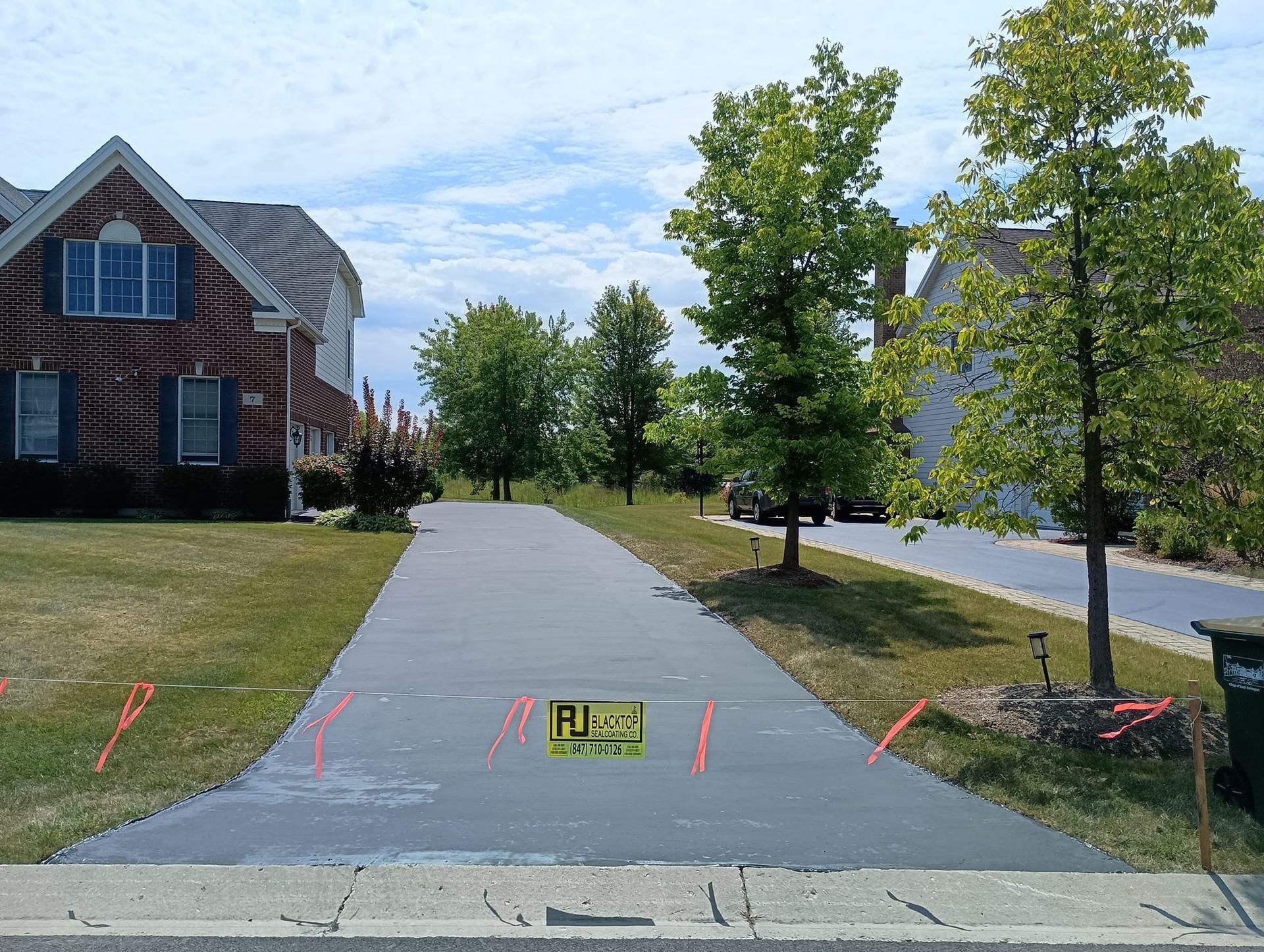 Driveway newly sealed with sealant. Residential neighborhood.