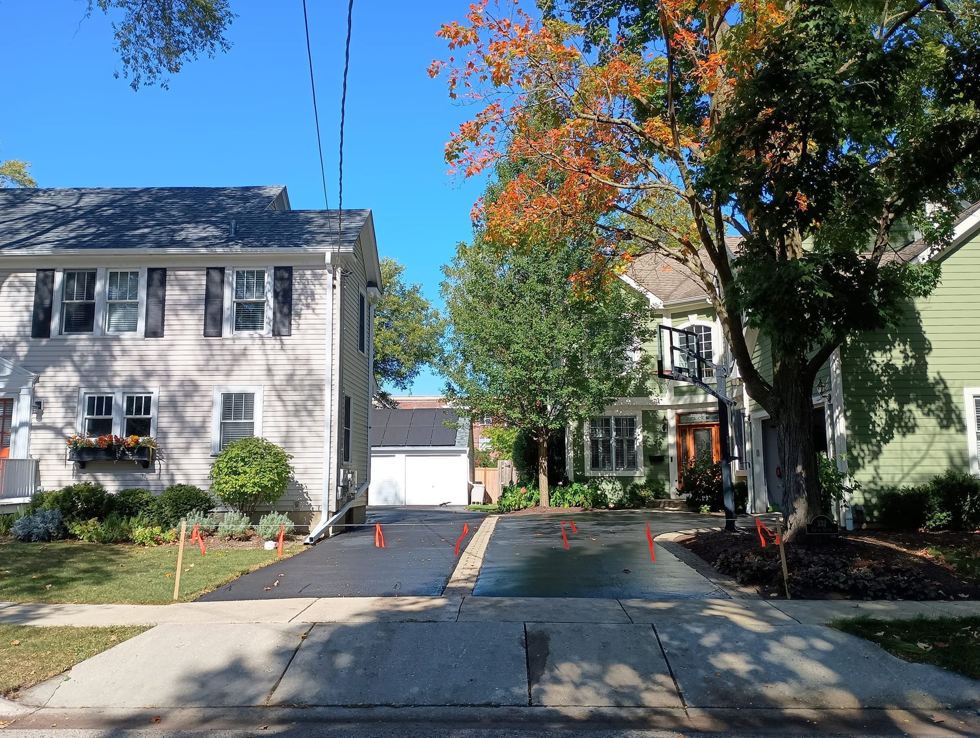 Driveways between houses; trees with fall foliage, sunny day.
