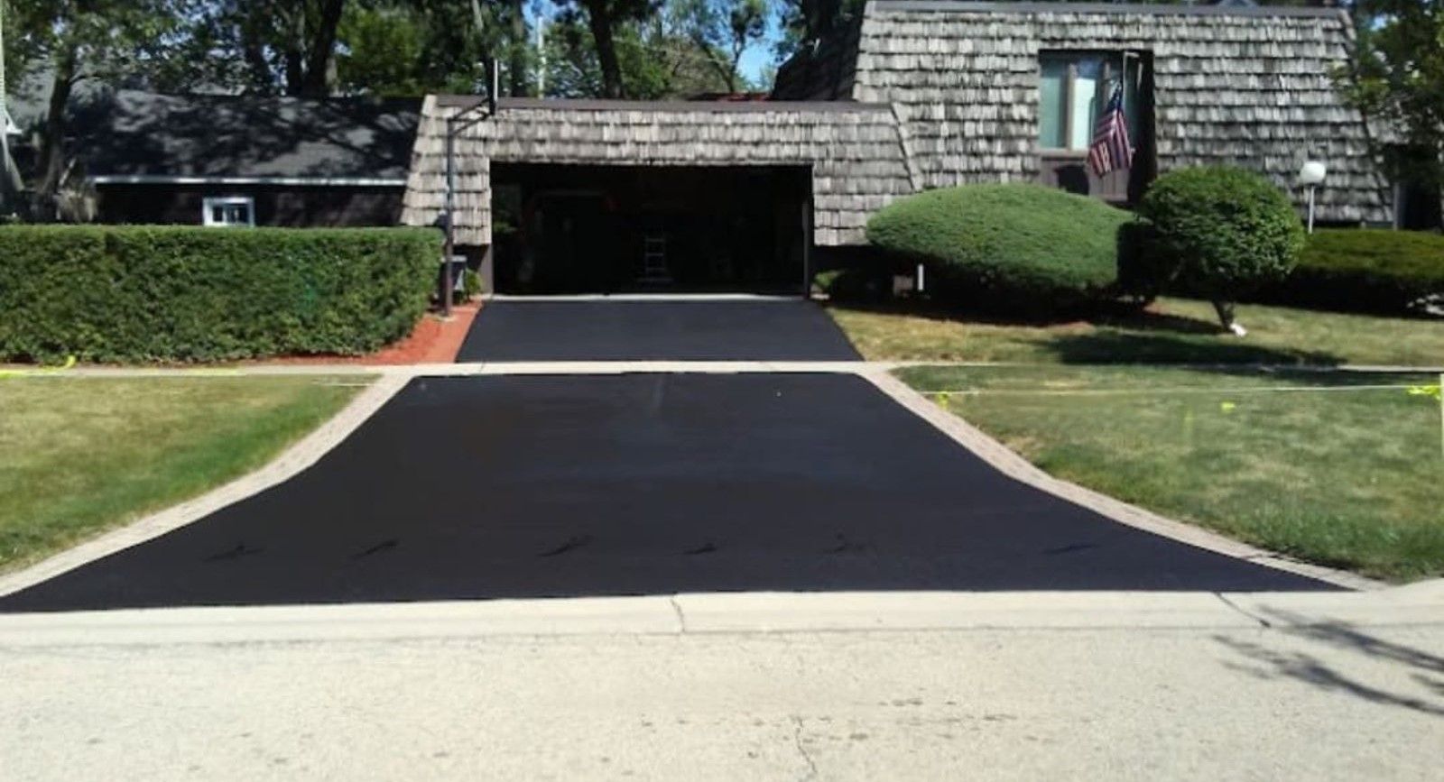 Black asphalt driveway leading to a house with a two-car garage.
