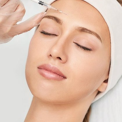 A woman is getting a botox injection on her forehead