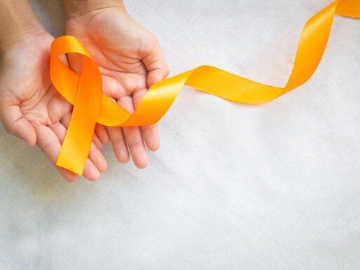 A person is holding an orange ribbon in their hands.