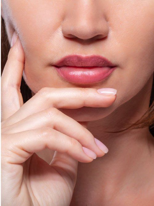 A close up of a woman 's face with her hand on her chin.