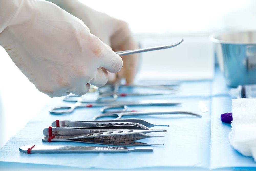 A person is holding a pair of scissors over a table with surgical instruments.