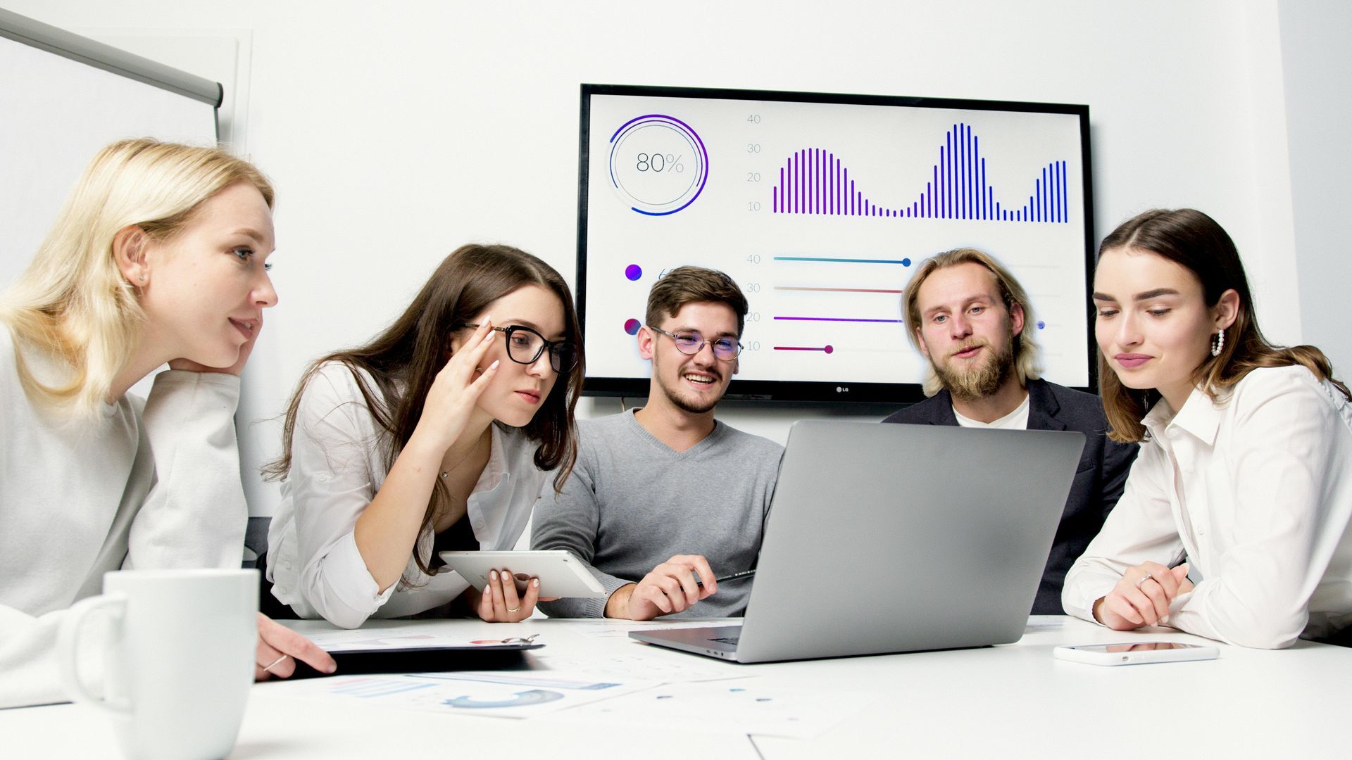 A group of people are sitting around a table looking at a laptop computer.