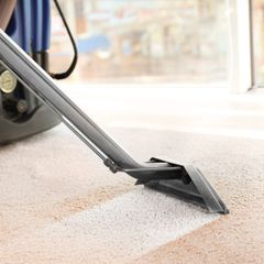 A person is using a vacuum cleaner to clean a carpet.