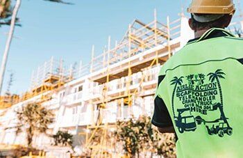 Tradie Standing In Front Of Scaffolding — Temporary fencing Whitsundays in Arlie Beach, QLD