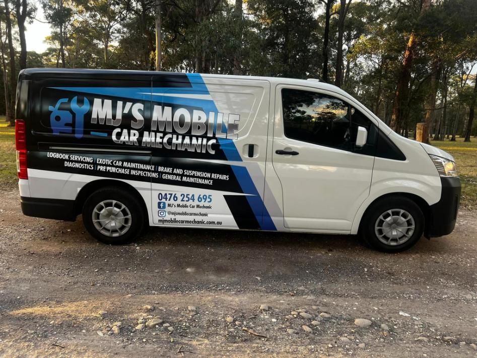 A White Van With A Blue And Black Stripe On The Side Is Parked On A Dirt Road — MJ's Mobile Car Mechanic In Camden, NSW