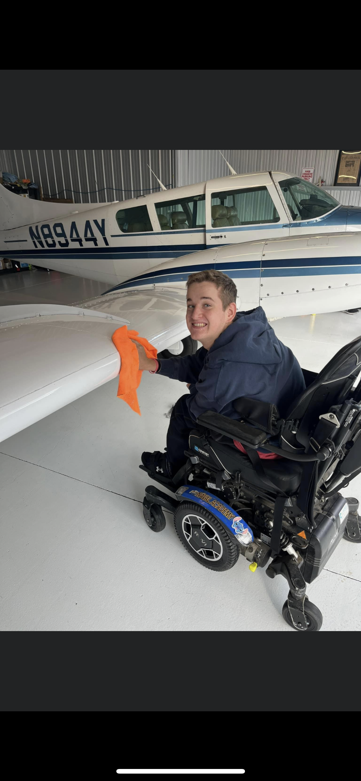 A man in a wheelchair is cleaning the wing of an airplane.