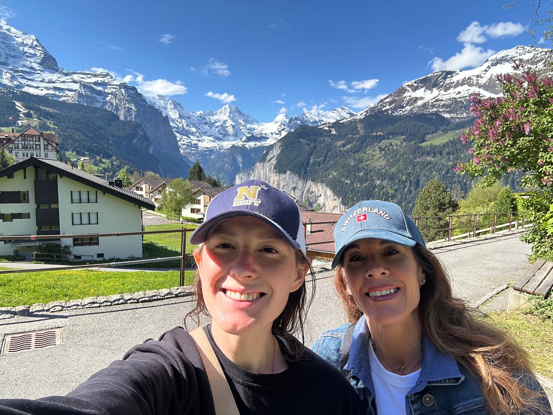 A woman is standing in front of a fence in front of a building.