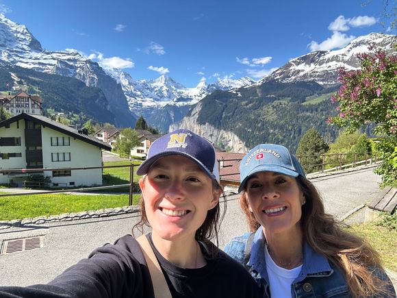 A woman is standing in front of a fence in front of a building.