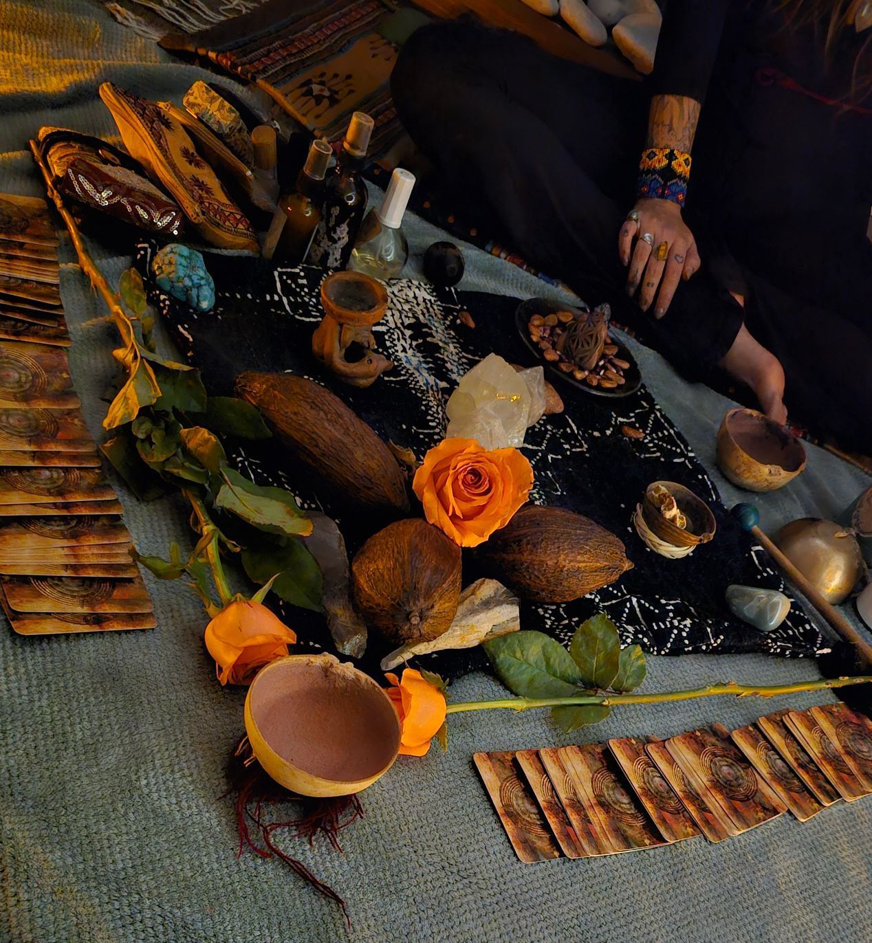 Una mujer se sienta en el suelo rodeada de cartas del tarot y flores.