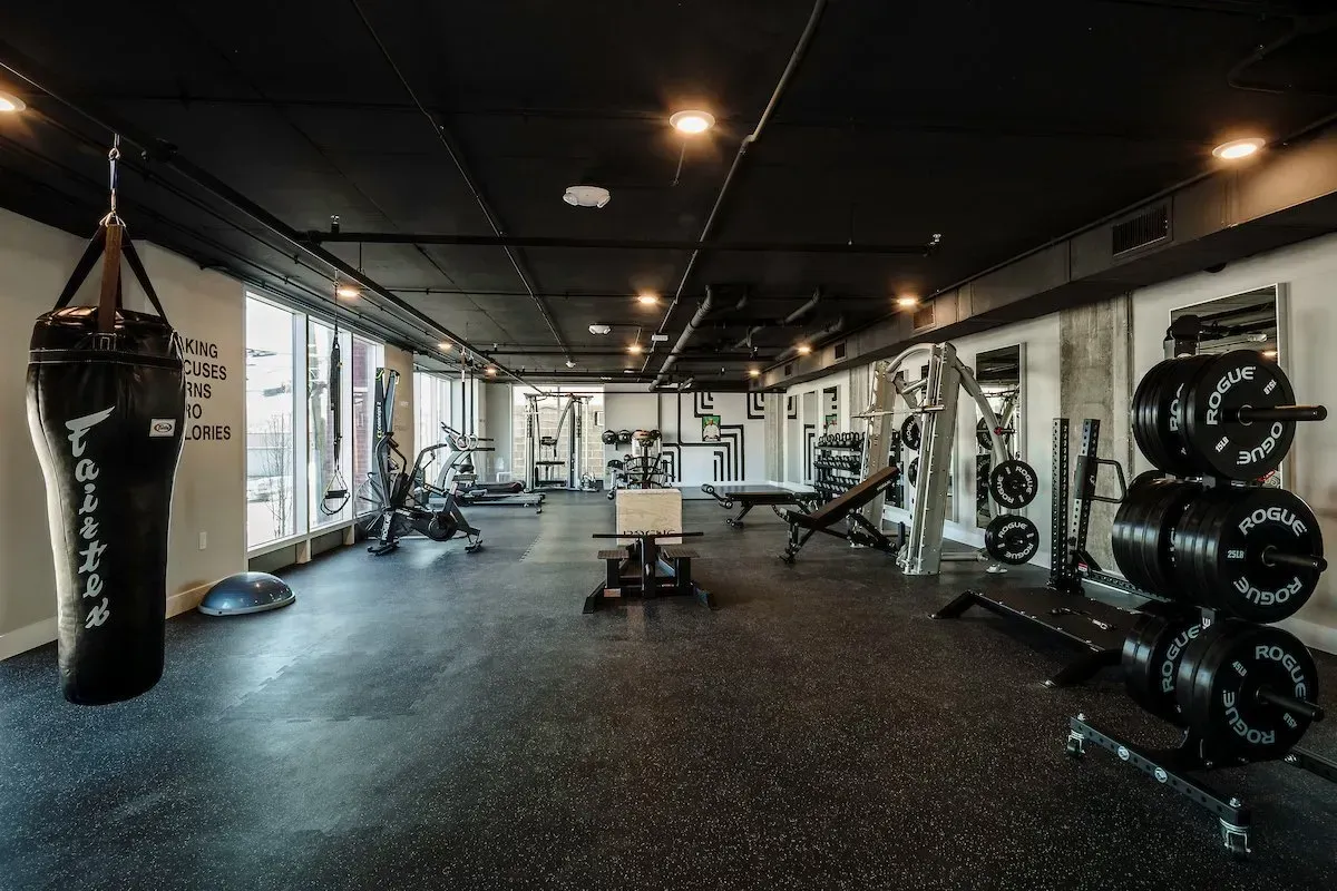 A large gym with a boxing bag hanging from the ceiling.