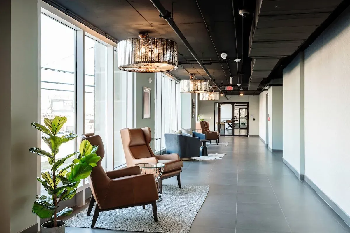 A long hallway with chairs and a plant in a building.