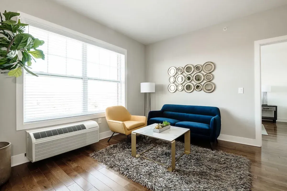 A living room with a couch , chair , coffee table and window.