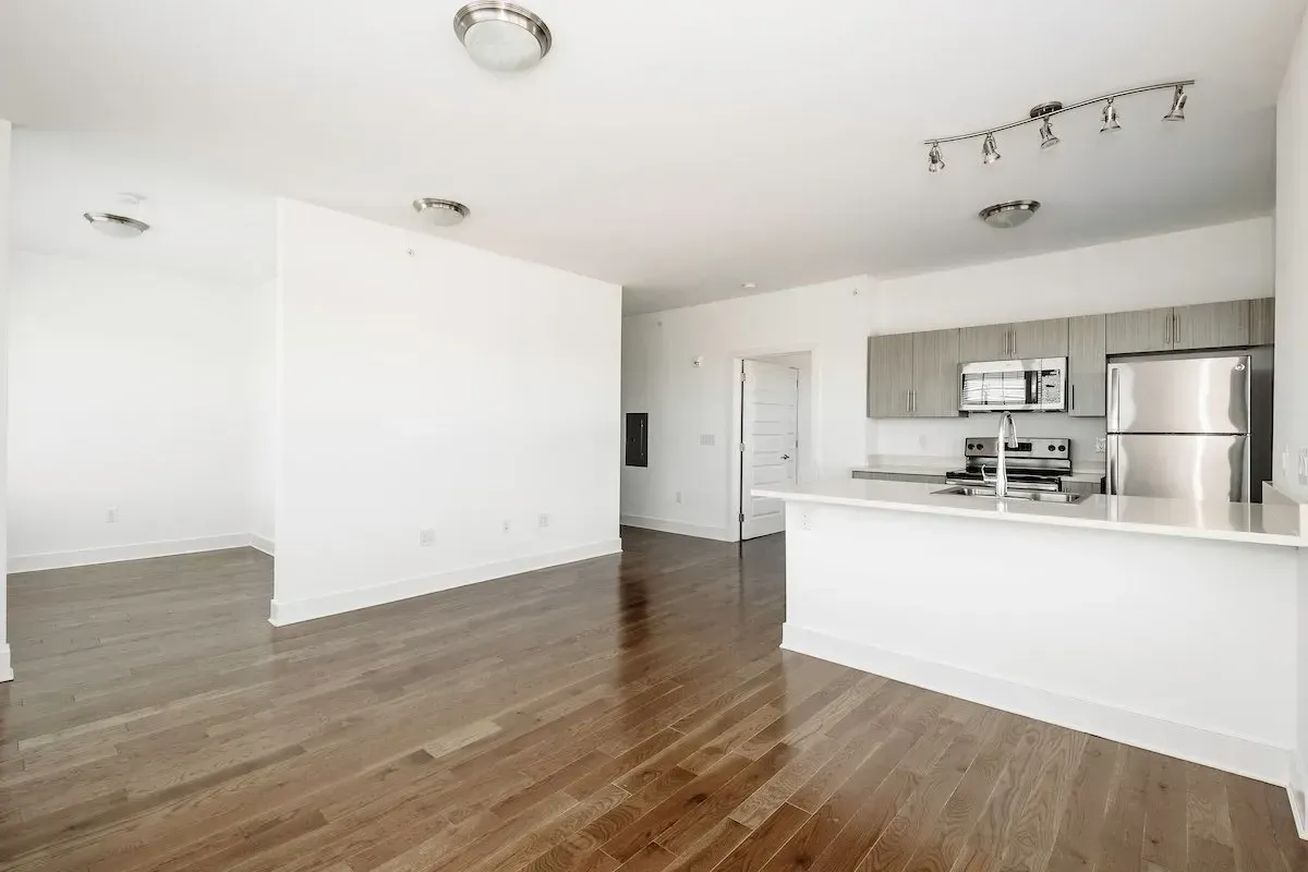 An empty apartment with hardwood floors and white walls