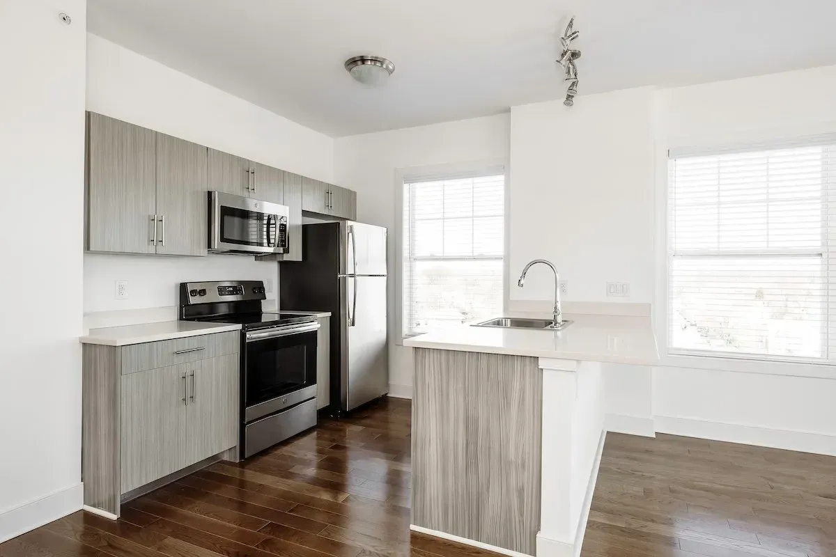 A kitchen with a stove , refrigerator , microwave and sink.