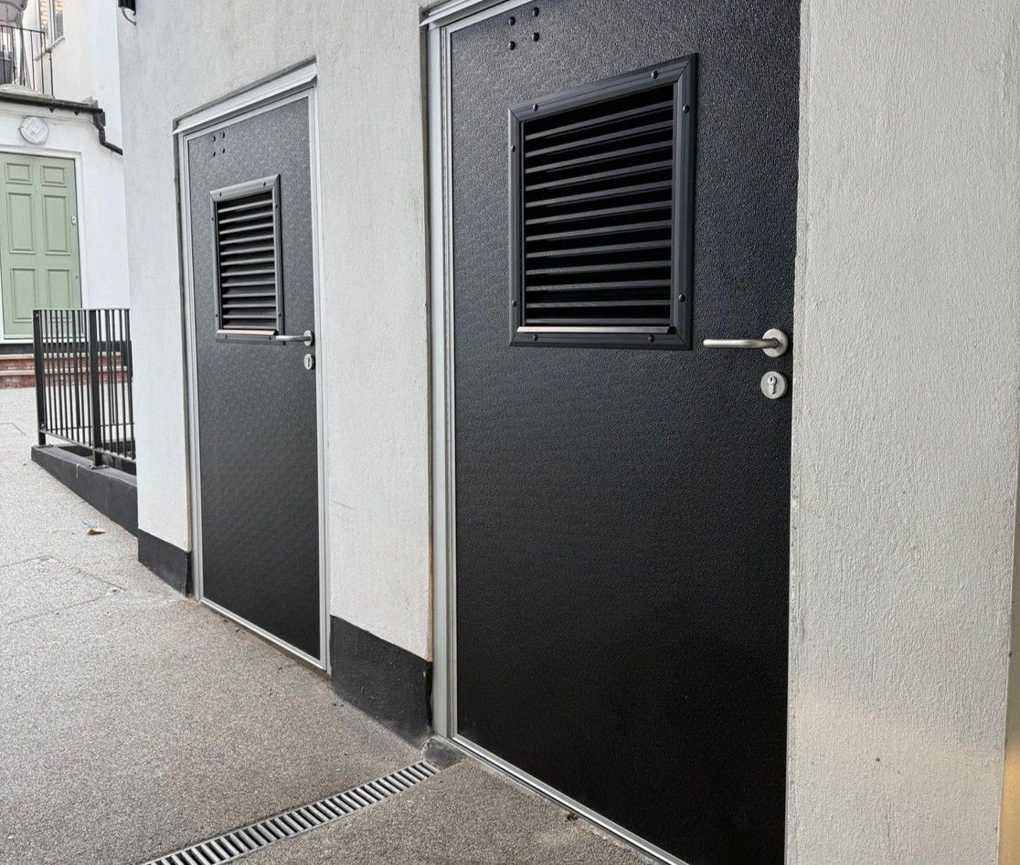 A large white building with a lot of windows and doors is sitting in a parking lot.