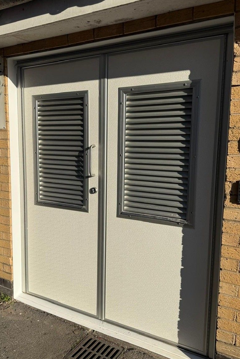 A large white building with a lot of windows and doors is sitting in a parking lot.