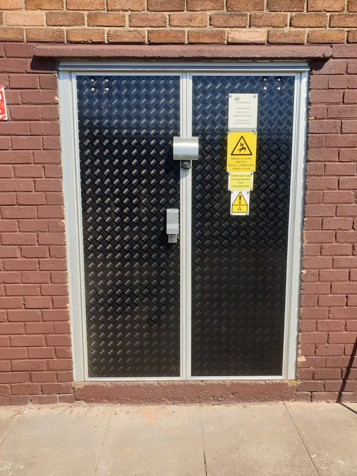 A black door with a warning sign on it