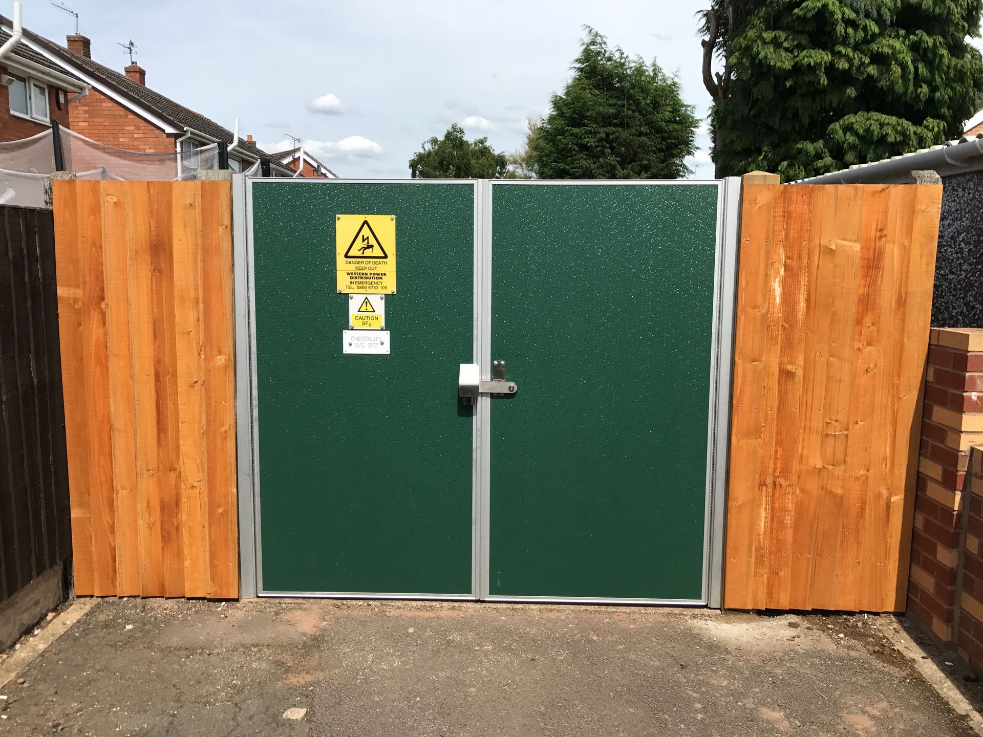A green gate with a yellow warning sign on it