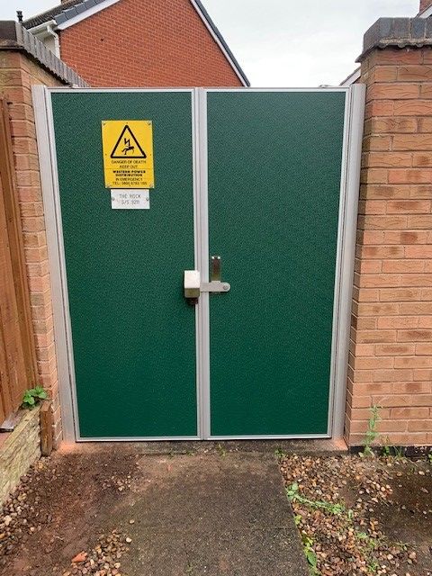 A green gate with a yellow warning sign on it