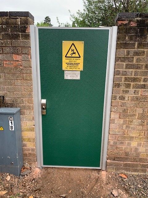 A green door with a yellow warning sign on it