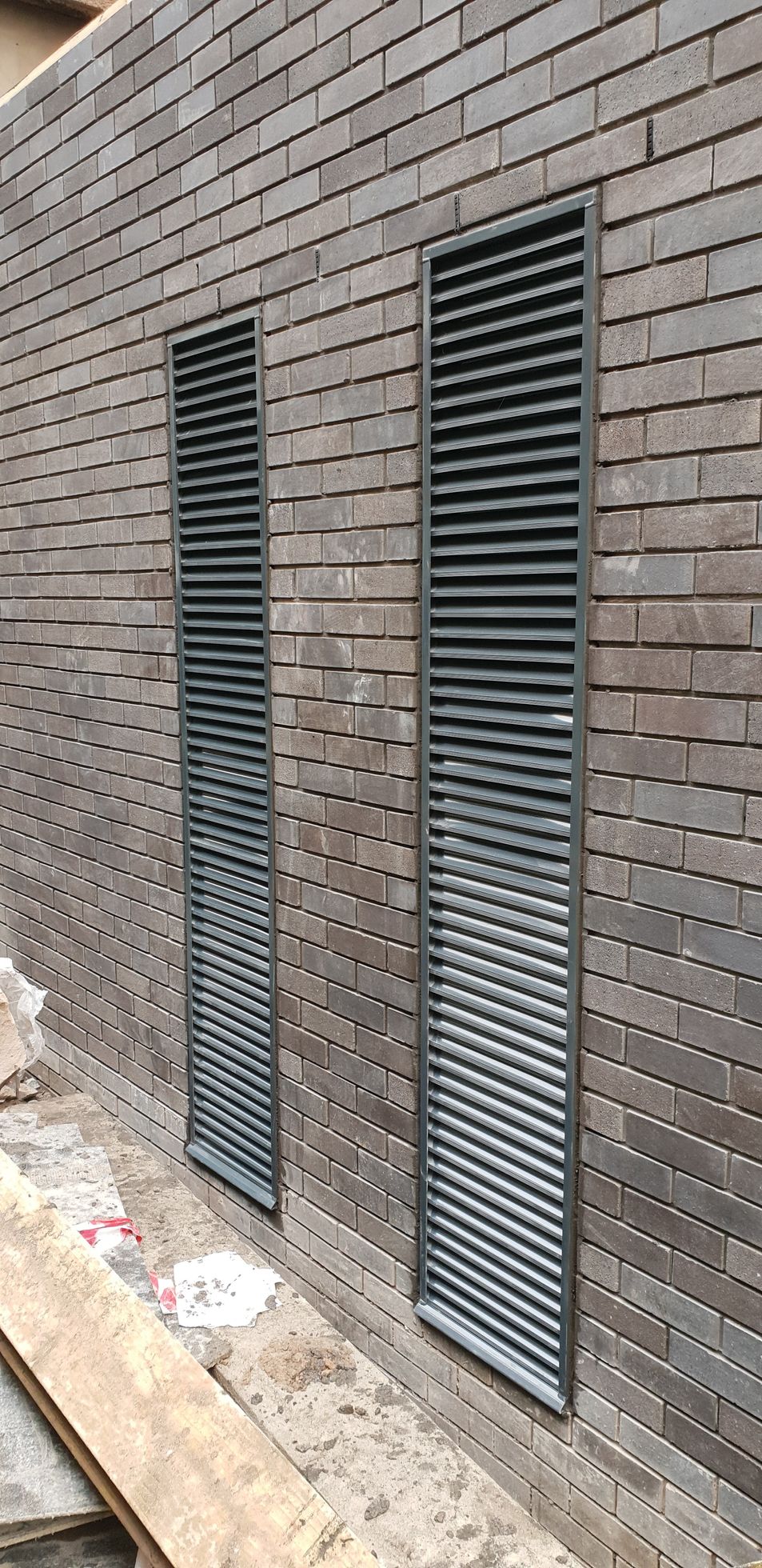 A brick wall with two metal shutters on it.