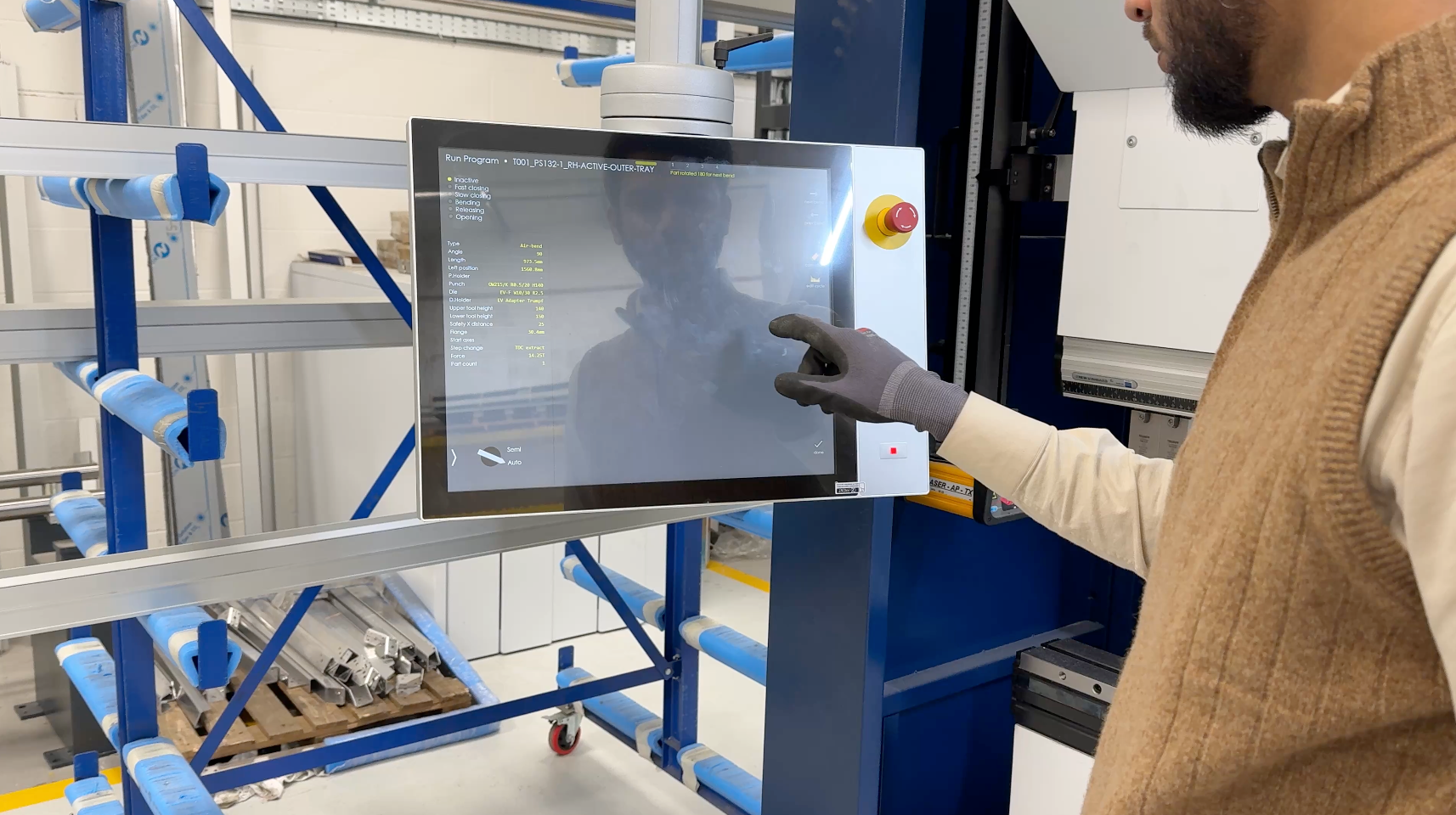 A man is cutting a piece of metal with a circular saw in a factory.
