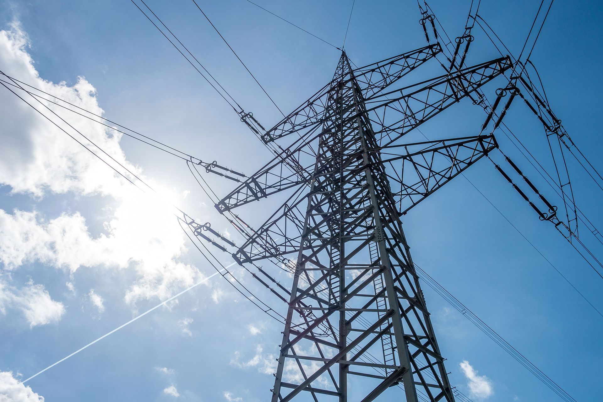 The sun is shining through the power lines on a sunny day.