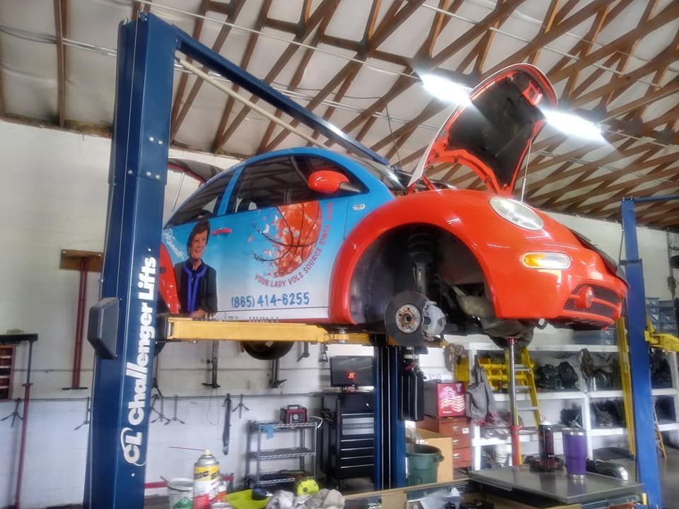 An orange car is on a challenger lift in a garage