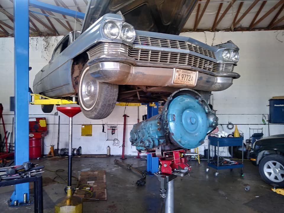 A car with a license plate that says 1776 is on a lift in a garage