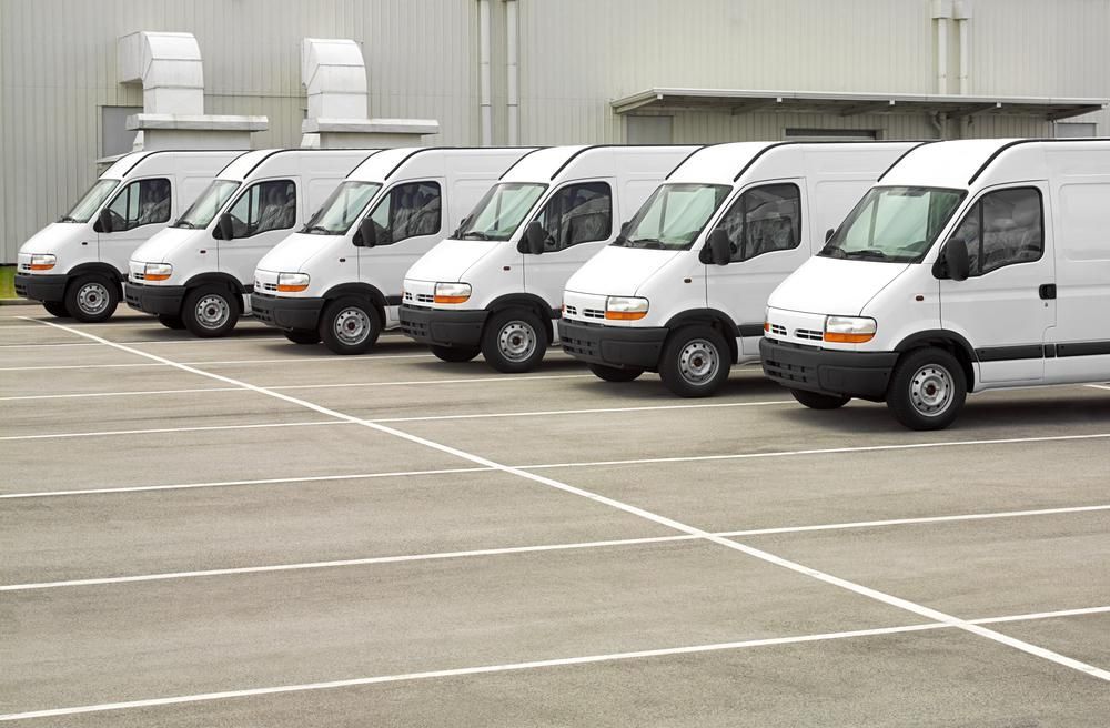 A Row Of White Vans Are Parked In A Parking Lot — Whitsunday Transfer Service In Hideaway Bay, QLD