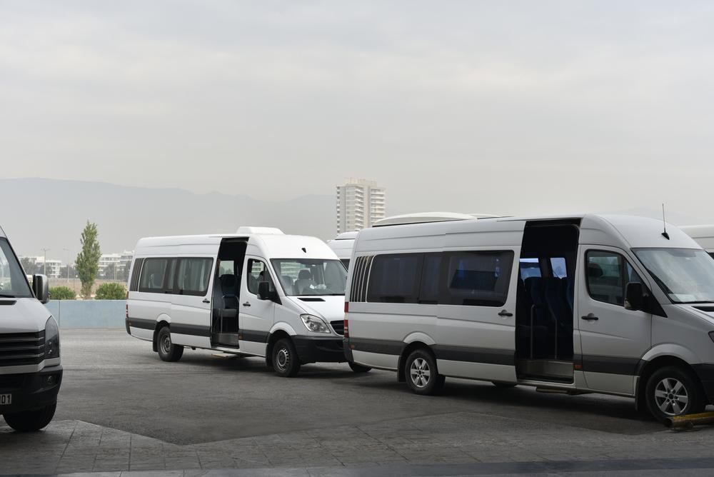 A Row Of White Vans Are Parked In A Parking Lot — Whitsunday Transfer Service In Dingo Beach, QLD