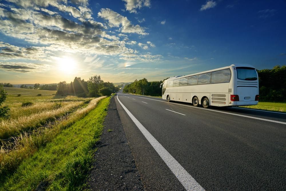 A White Bus Is Driving Down A Country Road — Whitsunday Transfer Service In Hideaway Bay, QLD