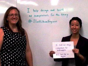 Two women standing in front of a white board that says i help design and build ad compressors for the navy