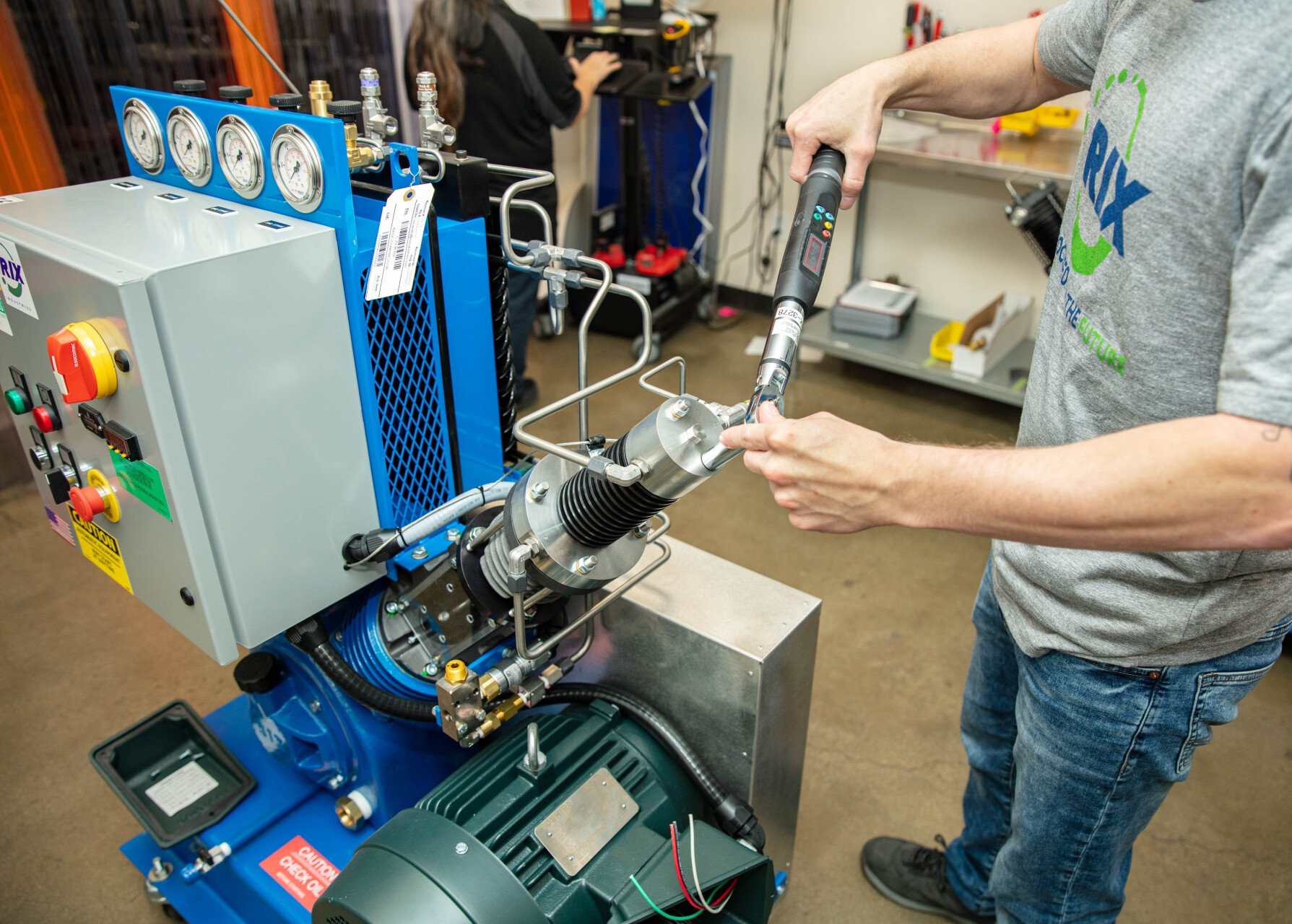 A man in a gray shirt is working on a machine.
