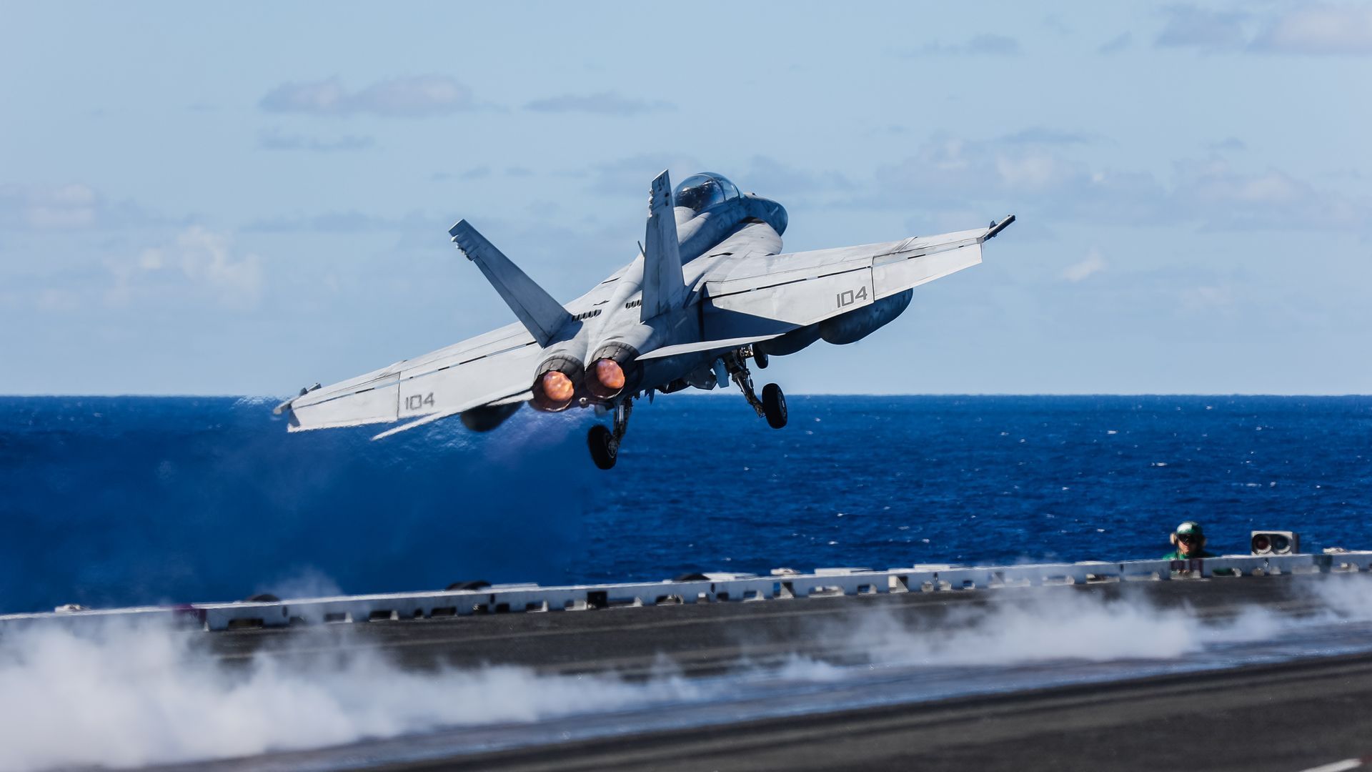 A fighter jet is taking off from a carrier.