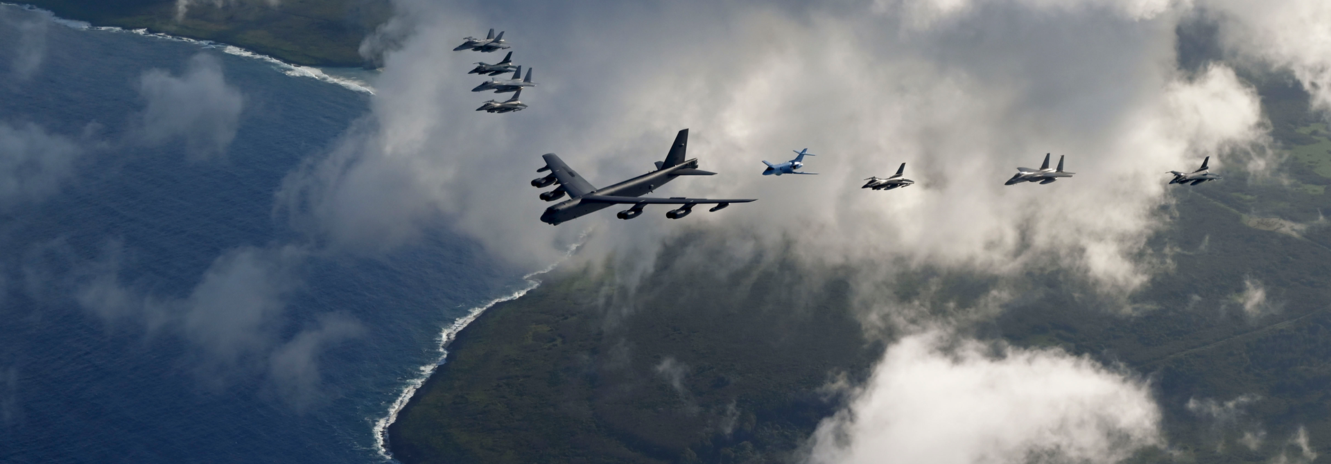 Photo of Air Force B-52 Stratofortress, a Navy E/A-18 Growler, a Marine Corps F/A-18 Hornet and Japanese aircraft fly in formation for a testing exercise.
