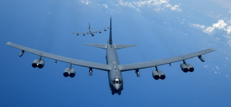A large military plane is flying through a blue sky.