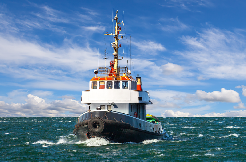 Photo of Tugboat on open ocean water with blue sky background