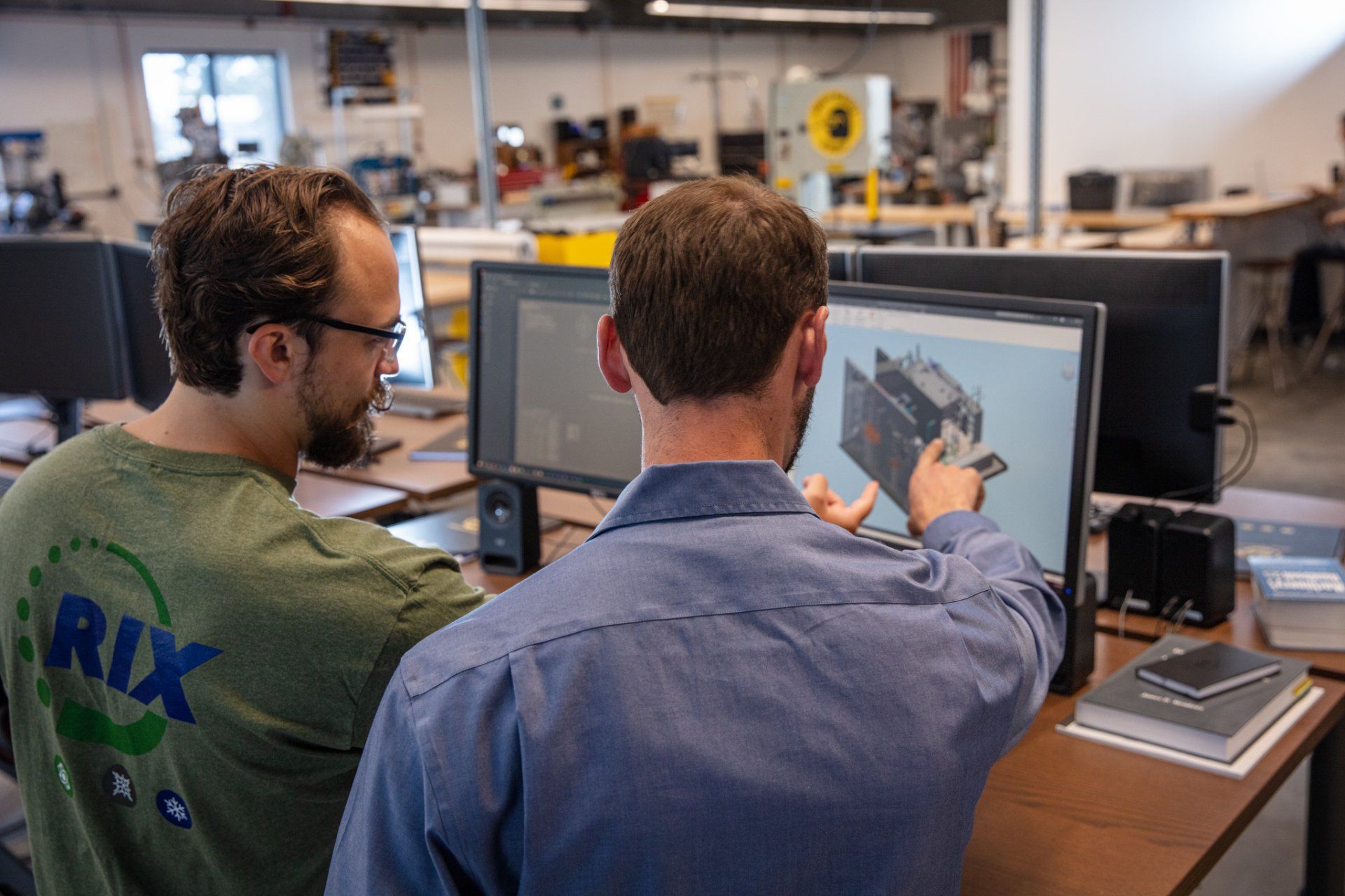 Two men are looking at a computer screen in an office.